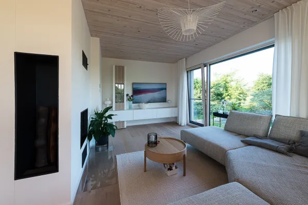 Wohnzimmer eines Holz100 Hauses mit Couch und weißer Wohnwand